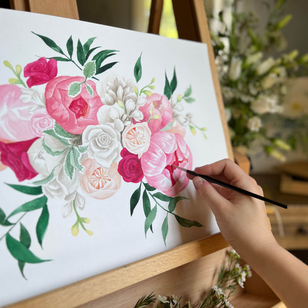artist hand painting a pink bouquet painting on easel