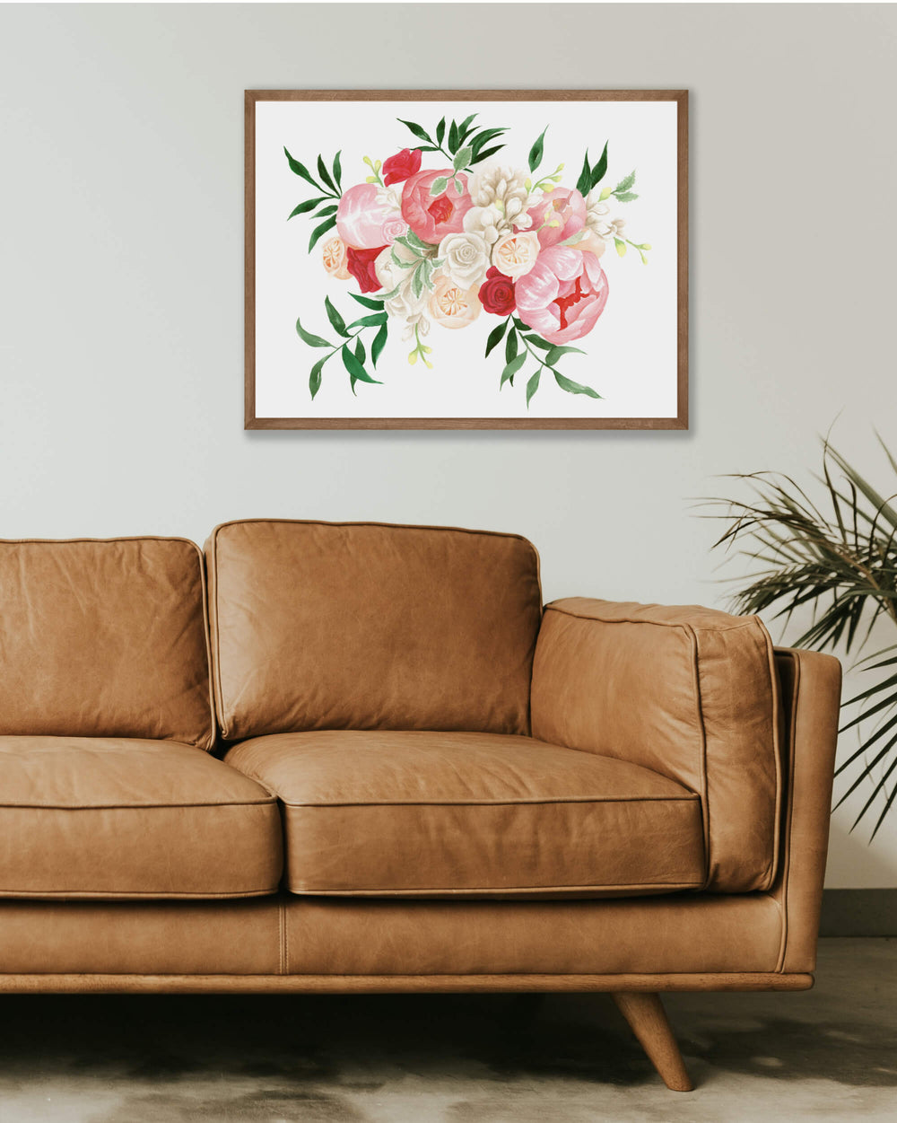 pink wedding bouquet painting on framed on wall above a leather couch and houseplant